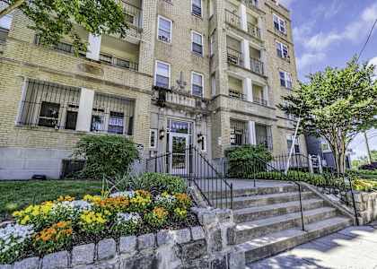 an apartment building with stairs and a garden in front of it