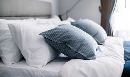 A bed with white and blue pillows.