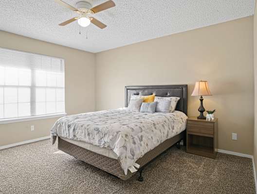 bed with white blanket and pillows next to large window