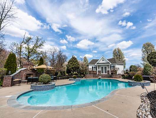 A large swimming pool in a backyard with a house in the background.