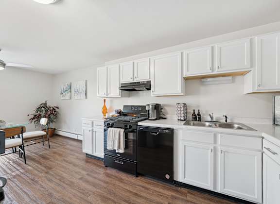 A kitchen with white cabinets and a black dishwasher.