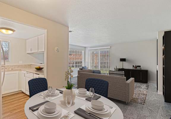 Dining area with view of kitchen leads into carpeted living room, with large window and sliding glass doors.at Capitol Crossing, Olympia, WA