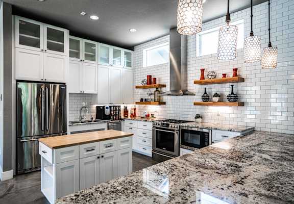 a kitchen with white cabinets and a marble counter top