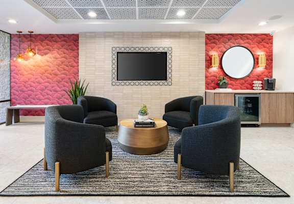 A living room with a red wallpaper and a television mounted on the wall.