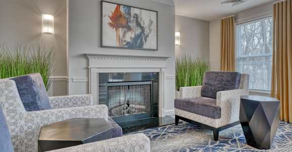 A living room with a fireplace and two chairs.