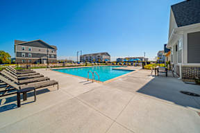 A swimming pool with sun loungers and a building in the background.