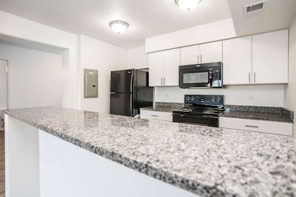 A kitchen with granite countertops and white cabinets.