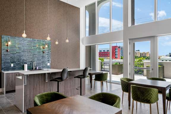 a dining room with green chairs and a kitchen with large windows