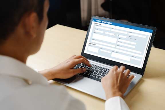 a woman typing on a laptop computer with an appointment scheduler on the screen