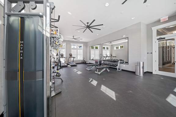 A gym with a treadmill, weights and mirrors.