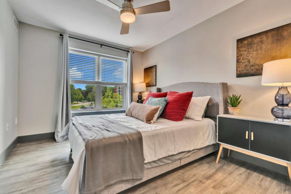 a bedroom with a large window and a ceiling fan