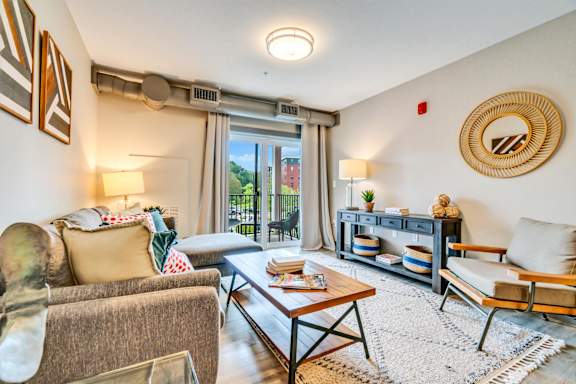 a living room with a couch coffee table and sliding glass door to a balcony