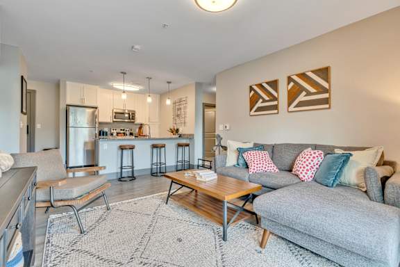 a living area with a couch coffee table and a kitchen in the background