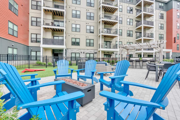 a firepit and chairs on a patio in front of an apartment building