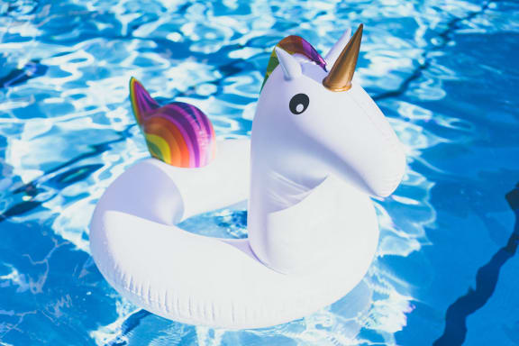 a unicorn pool float with a rainbow unicorn tail in a pool
