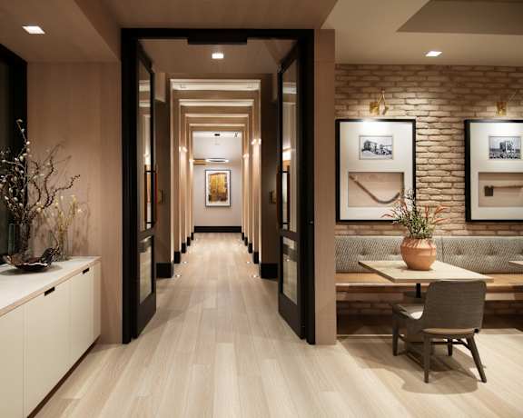 A long, narrow hallway with a bench and a table with a vase on it.
