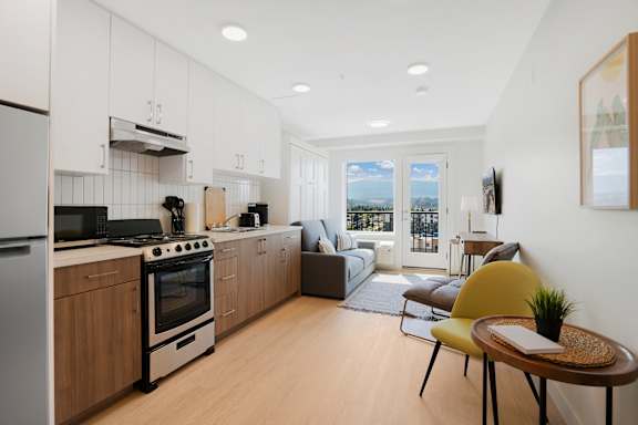 A modern kitchen with a yellow chair and a table with a plant on it.