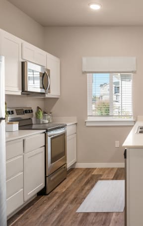 an open kitchen and dining area with a white counter top and a stainless steel refrigerator at Southside Townhomes, Idaho, 83686