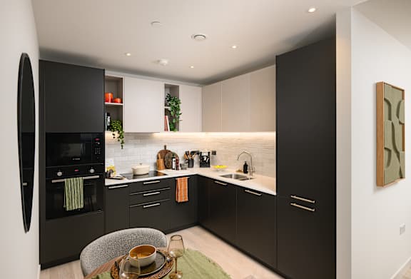 A modern kitchen with black cabinets and a wooden table.