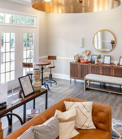 A living room with a brown sofa and a round mirror on the wall.
