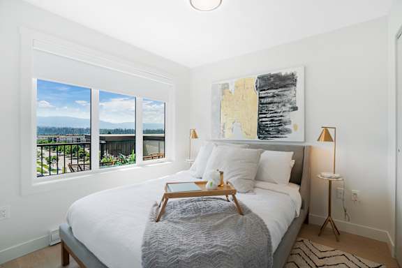 A bedroom with a large bed, a lamp, and a painting on the wall.