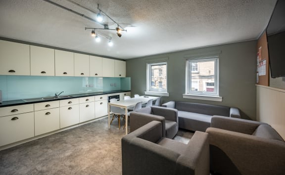 a living room and kitchen with couches and chairs and a table