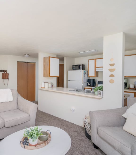 a living room with couches a table and a chair and a kitchen in the background  at Ironwood Apartments, Coeur d'Alene, 83814