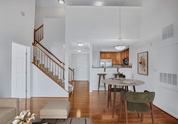A living room with a staircase and a dining table.