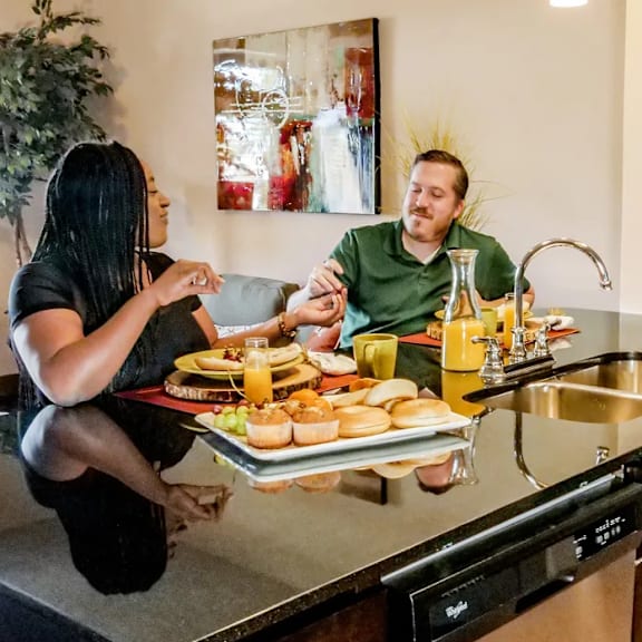 A man and a woman cooking food on a grill at Century Plaza Apartment Homes.