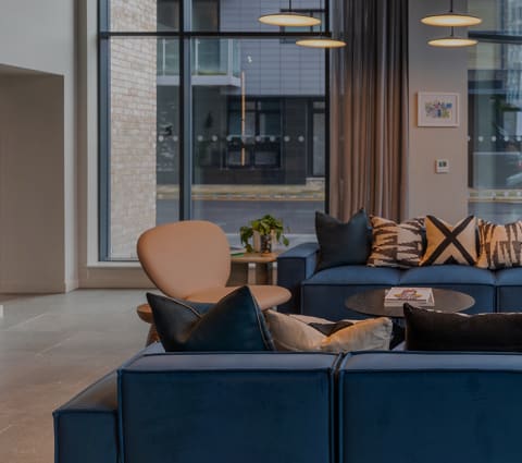 a living room with blue couches and chairs and large windows