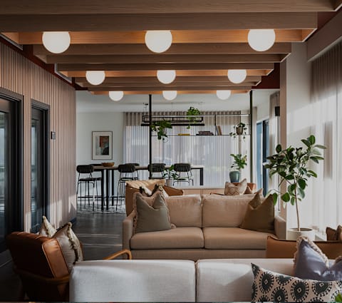 A living room with a beige couch and a wooden ceiling.