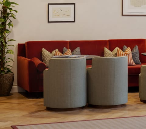 a living room with two rattan chairs and a red couch