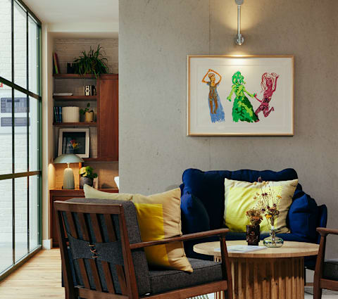 A living room with a blue couch, a wooden chair, and a painting on the wall.
