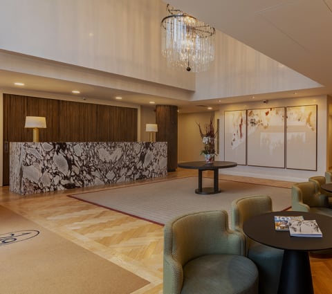a lobby with a reception desk and chairs and a chandelier