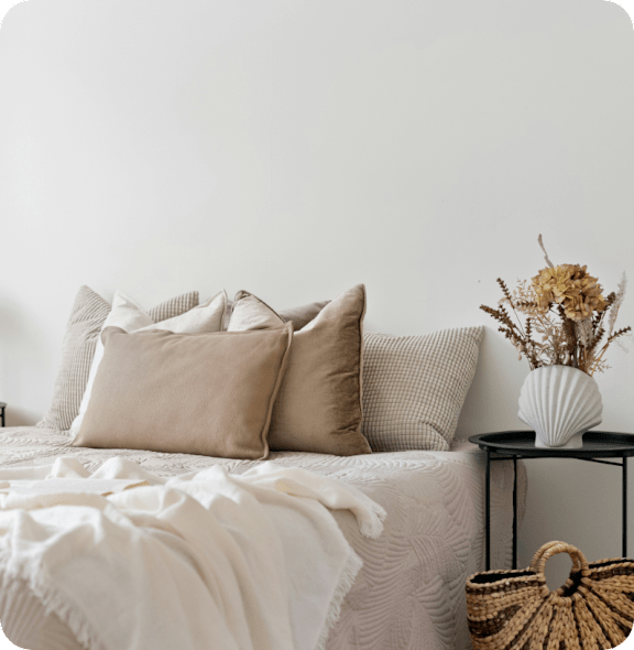 Bed with White Comforter and Pillows next to Vase with Flowers