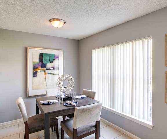 A dining room with a table set for two and a window with blinds.