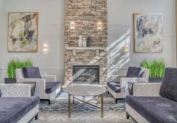 A living room with a stone fireplace and grey couches.