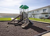 Thumbnail 10 of 10 - A playground with a slide and a green canopy.