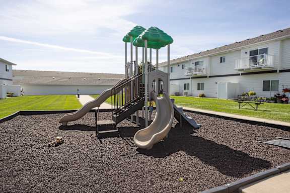 A playground with a slide and a green canopy.