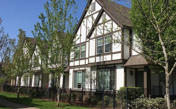 a house with a fence and trees in front of it