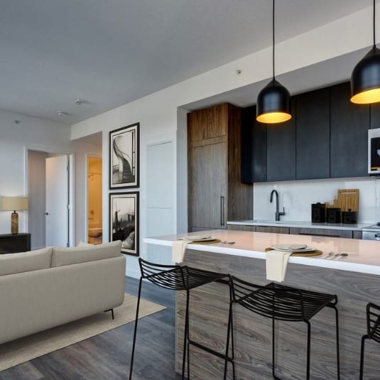 clean modern interior of a grey couch and sleek kitchen at Citizen on Jasper, Edmonton, Alberta, T5K 0P3