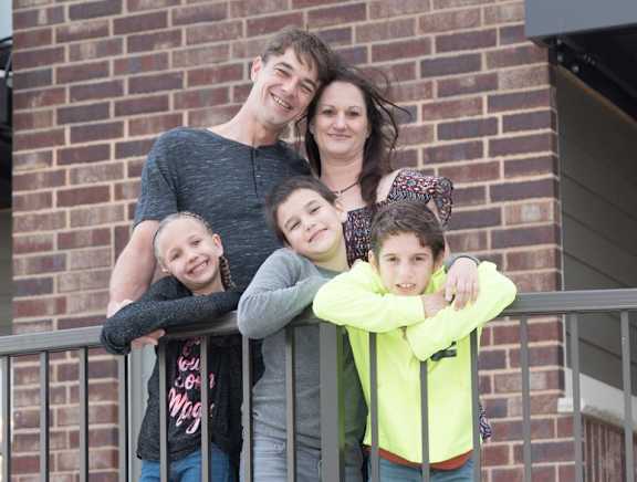 A family of four posing together on a balcony.