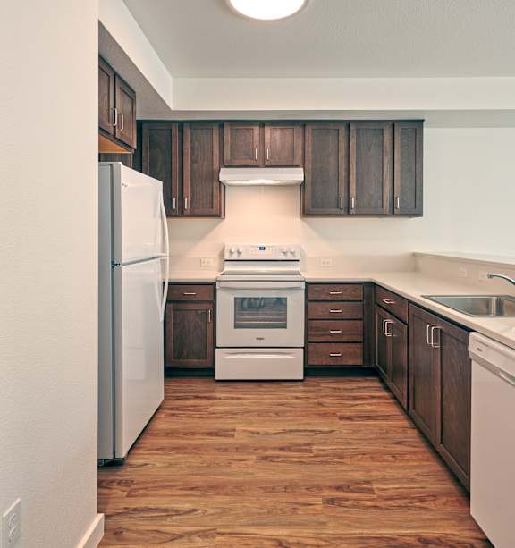 A kitchen with wooden floors and white appliances.