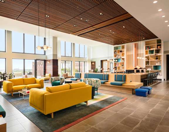 a large lobby with yellow couches and chairs and a library