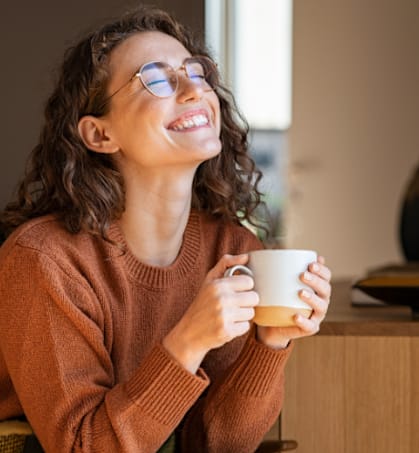 a woman smiling while holding a cup of coffee