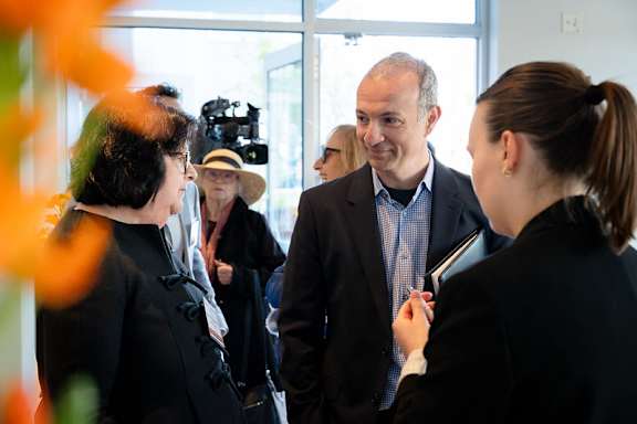 A man in a suit is talking to a woman in a black blazer.