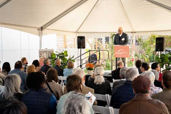 A man is giving a speech at an outdoor event.