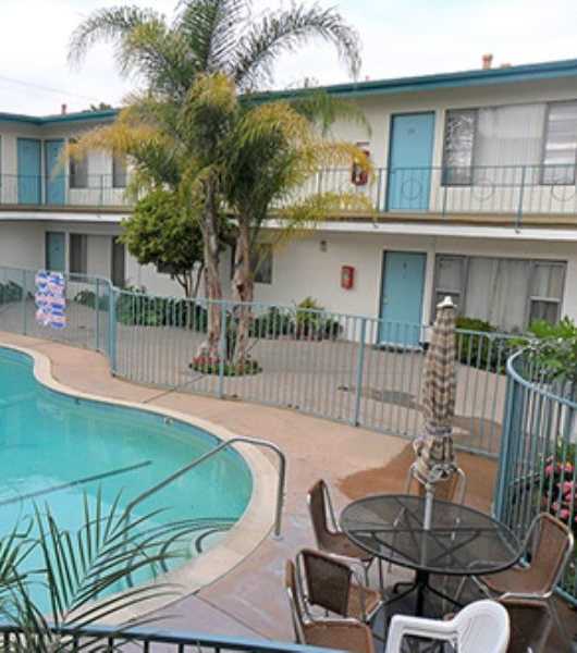 A pool with a hot tub and lounge chairs in front of a building.
