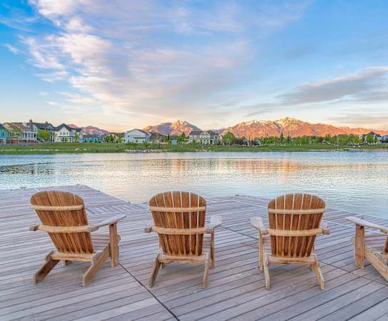 a row of wooden chairs sitting on a dock overlooking a lake