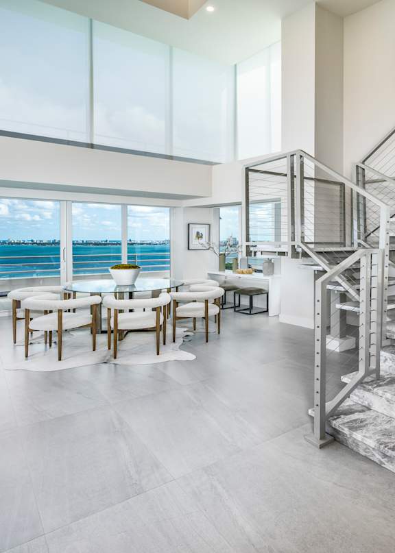 A modern living room with white furniture and a staircase in the background. at The Hamilton, Miami, FL